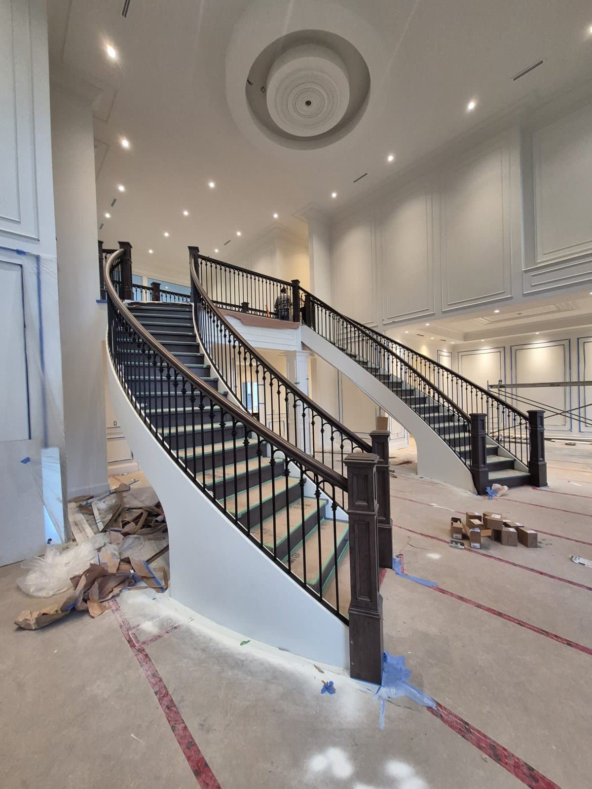 Sweeping double staircase with black metal balusters and a dark wood handrail