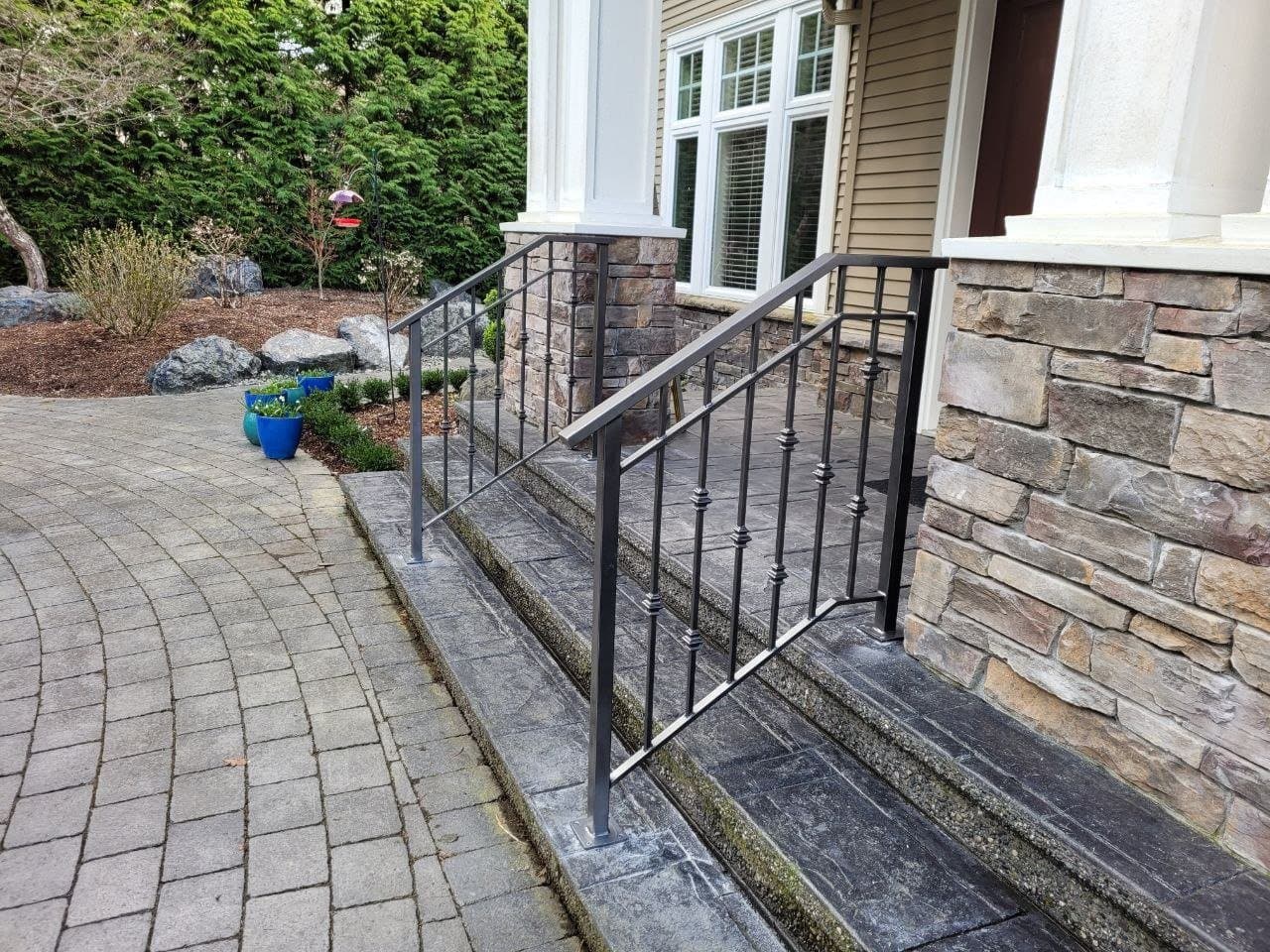 Black picket railing beside stone-clad front steps