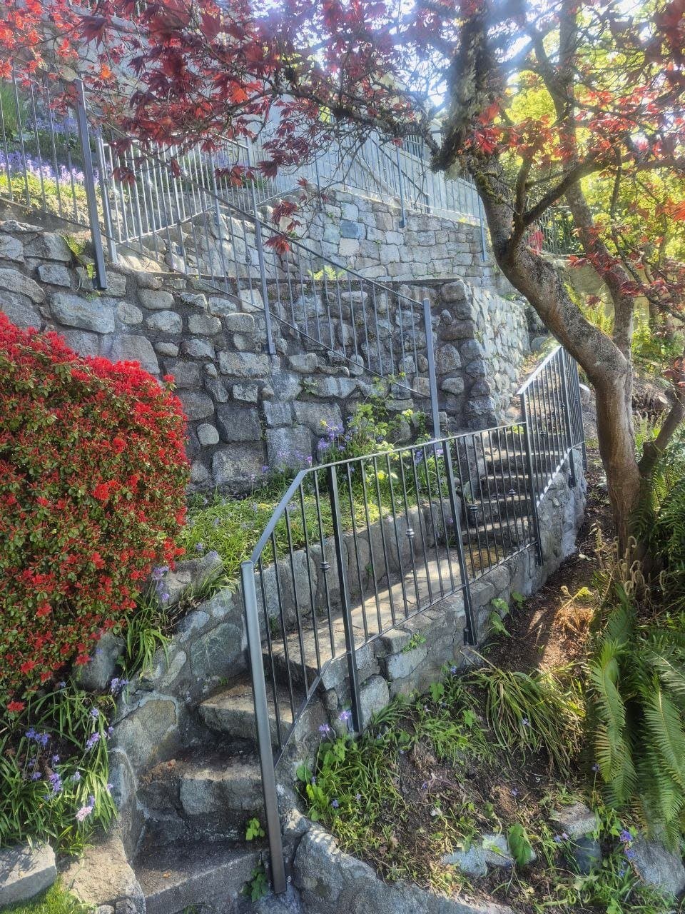 Black metal handrail following stone garden stairs