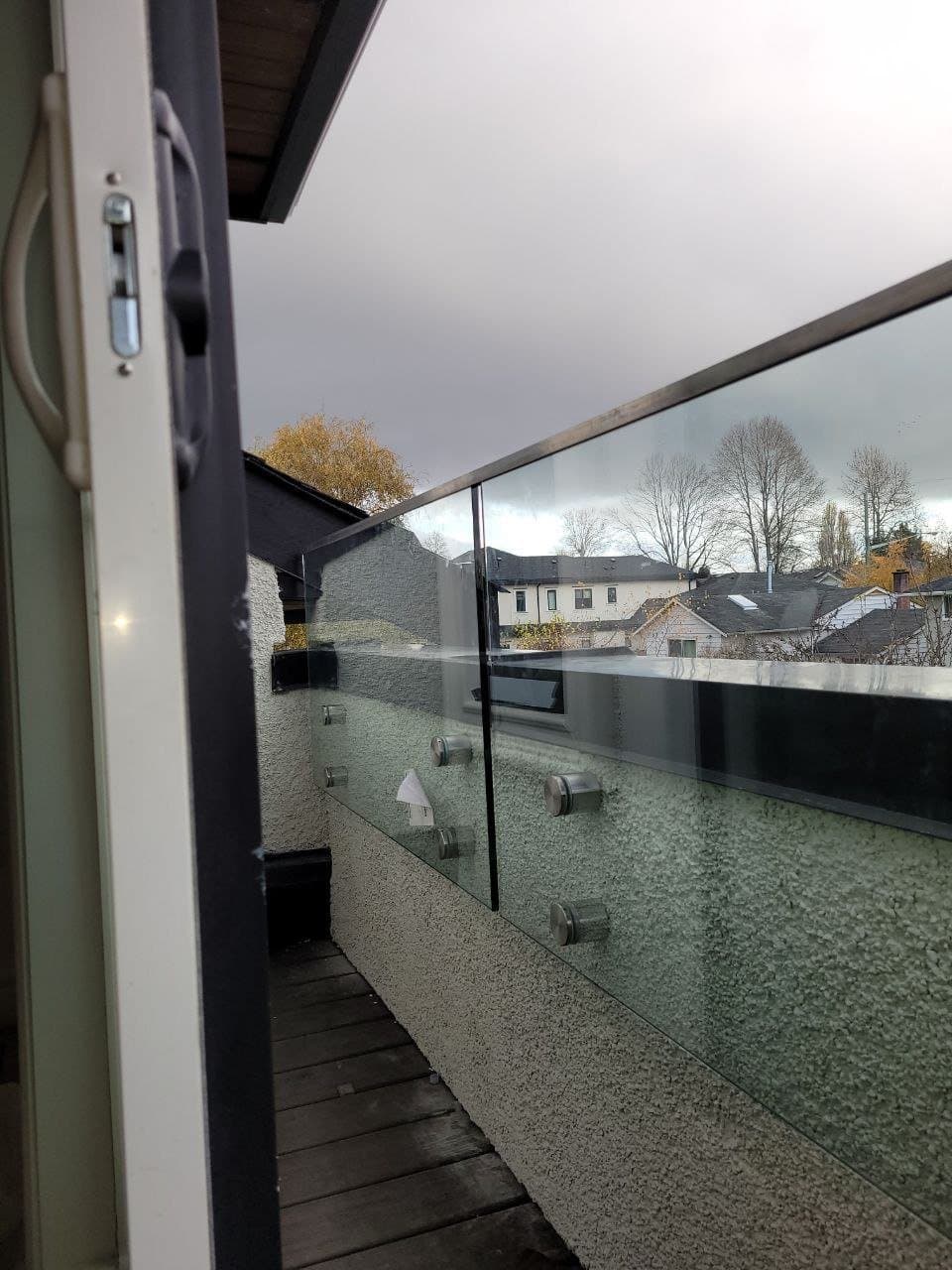 Glass panel balcony railing with a metal top rail