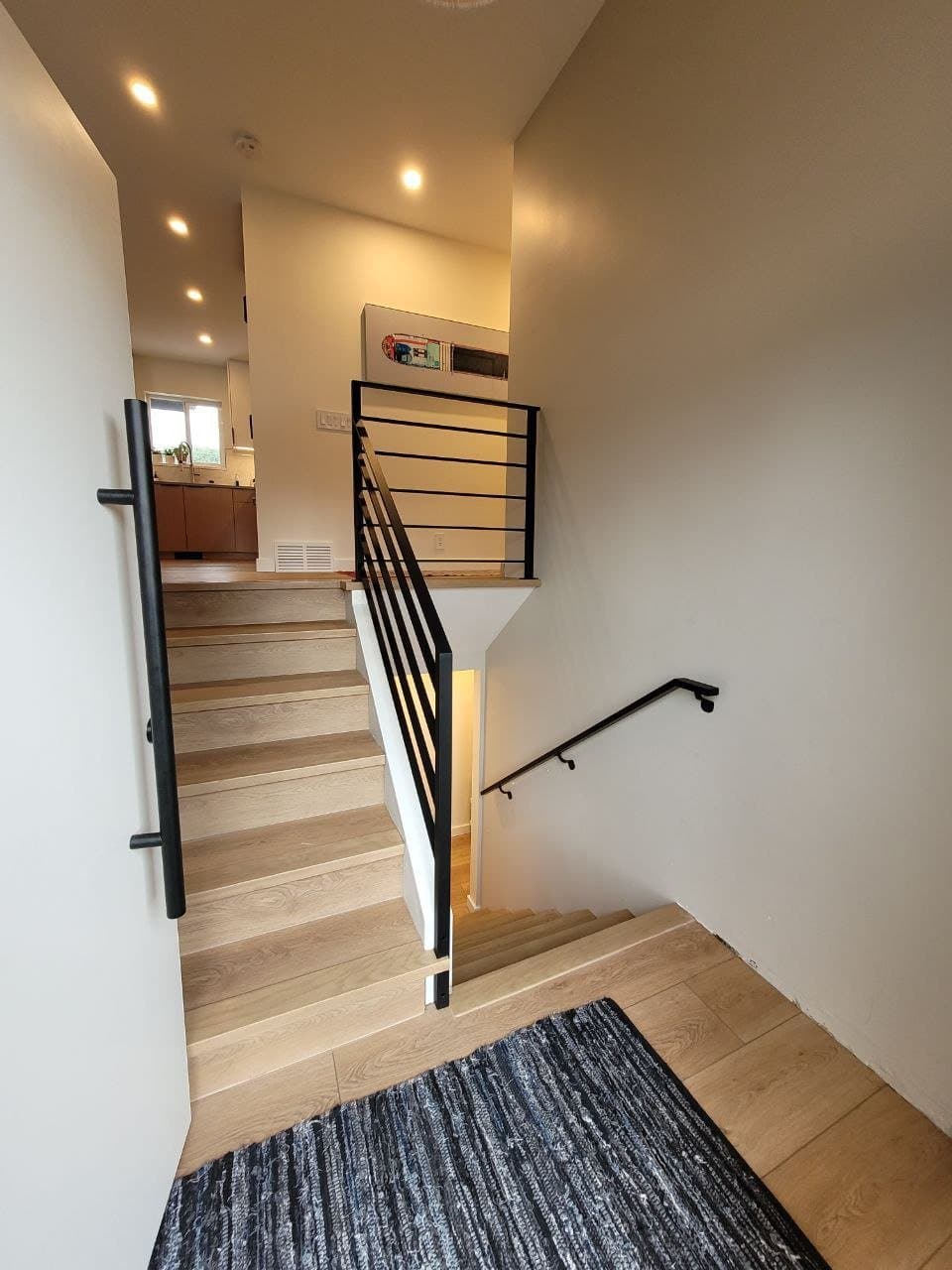Black horizontal bar railing and wall handrail on an interior staircase