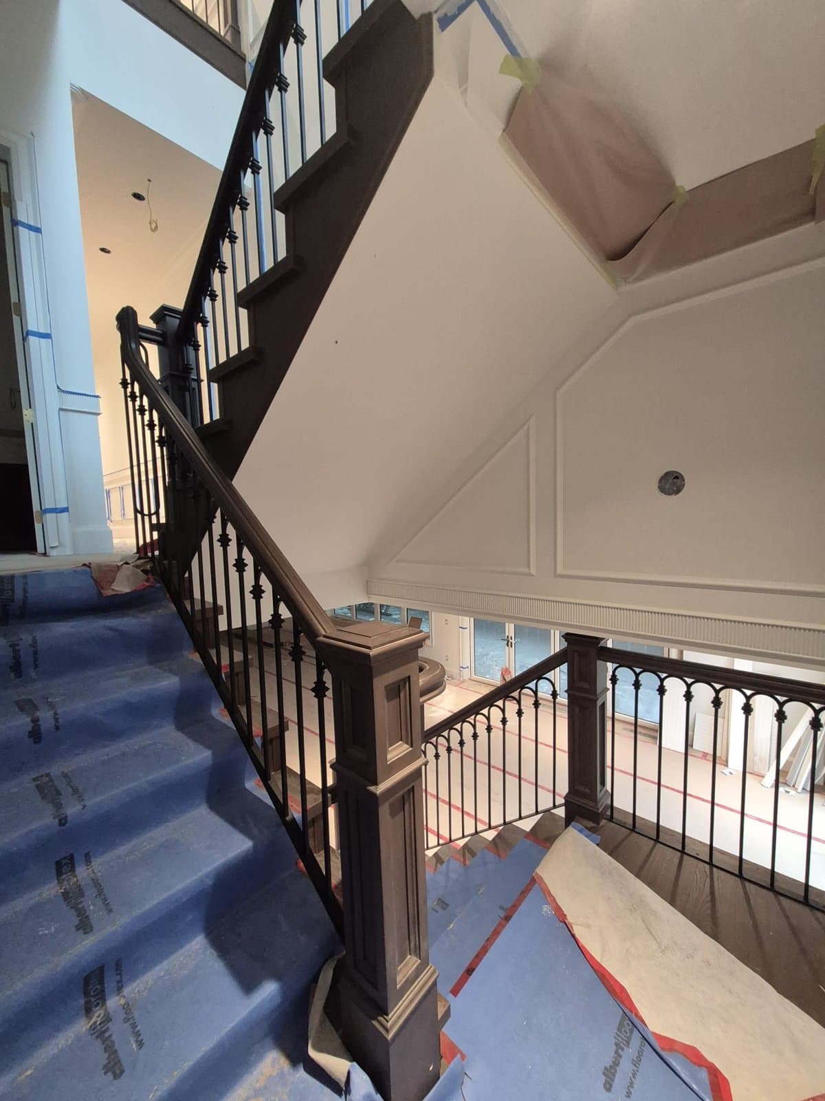 Staircase with black balusters and a wood newel post