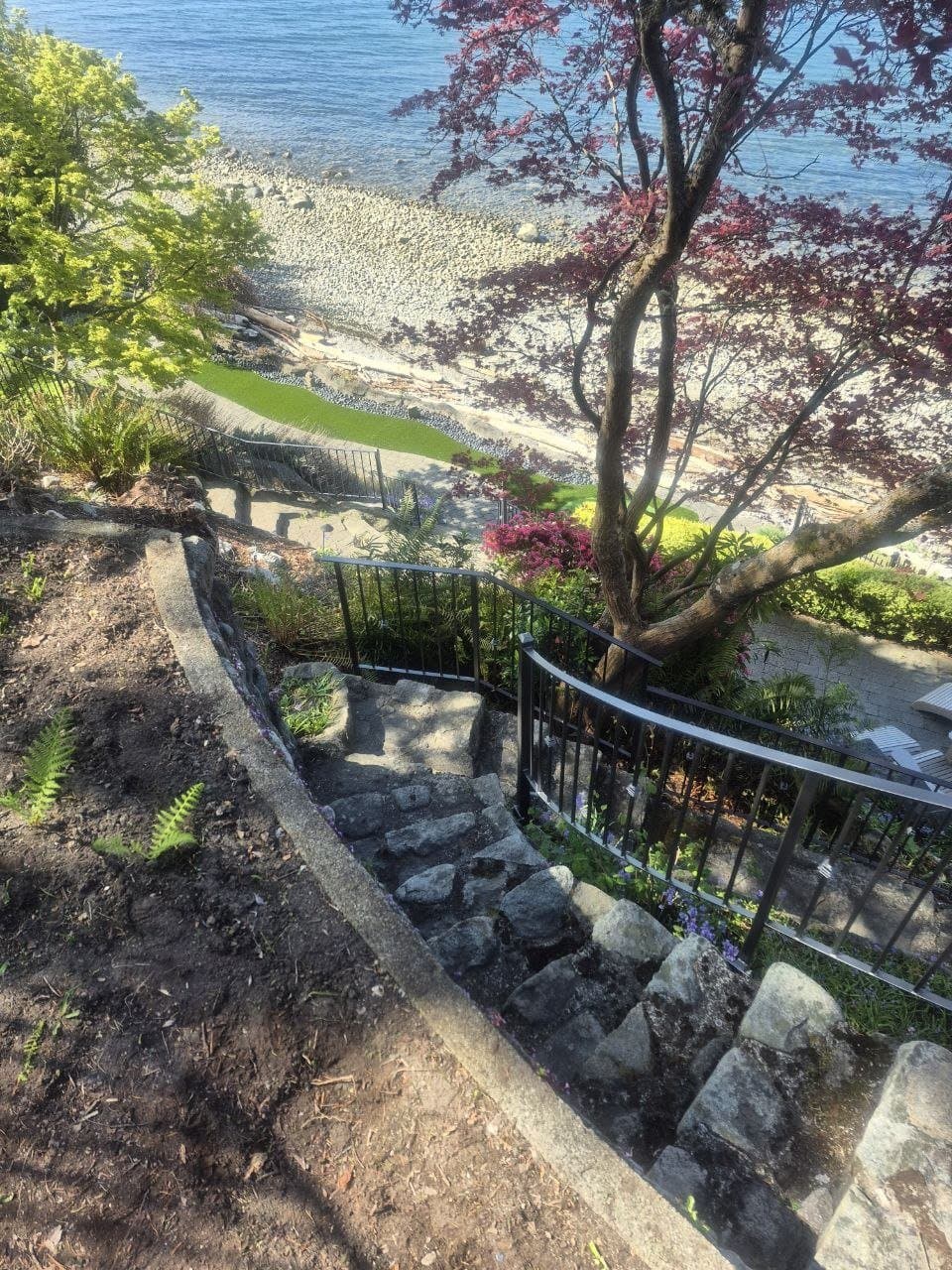 Curved black picket railing along a garden path above the beach